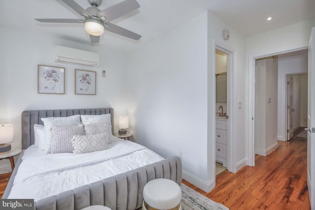 bedroom featuring hardwood / wood-style flooring, a wall unit AC, ceiling fan, and sink