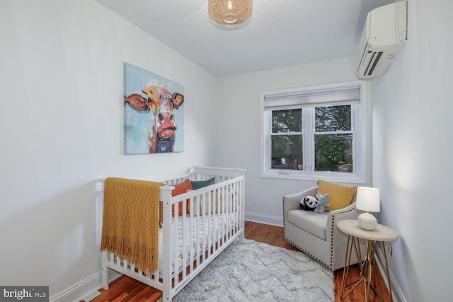 bedroom with a wall mounted air conditioner, wood-type flooring, and a crib