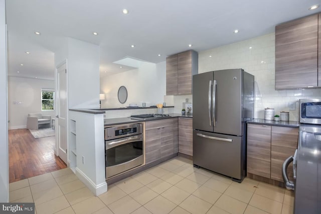 kitchen featuring stainless steel appliances, tasteful backsplash, and light tile patterned flooring