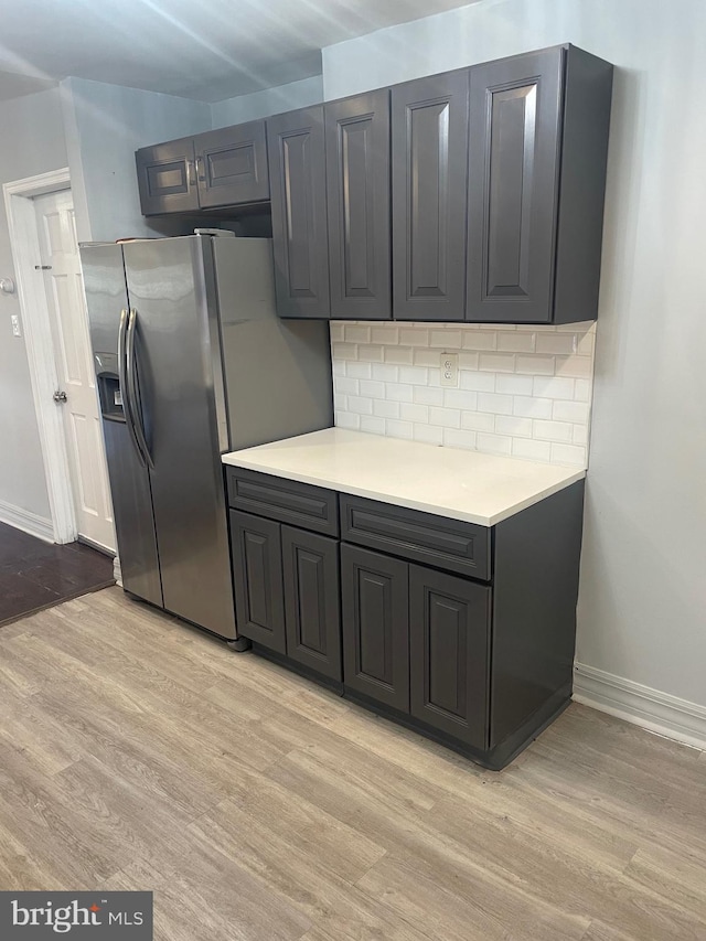 kitchen featuring light wood-type flooring, stainless steel fridge, and decorative backsplash