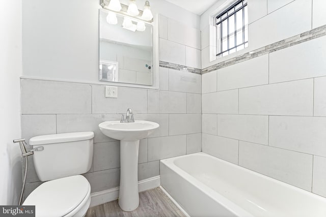 full bathroom with separate shower and tub, sink, wood-type flooring, tile walls, and toilet