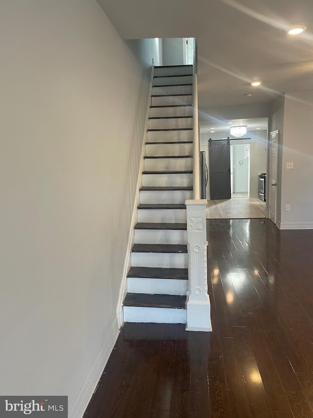 stairway featuring a barn door and hardwood / wood-style flooring