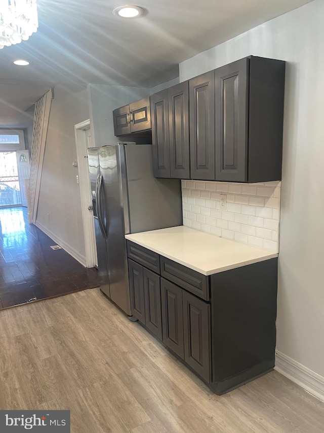 kitchen with decorative backsplash, stainless steel fridge with ice dispenser, and light wood-type flooring