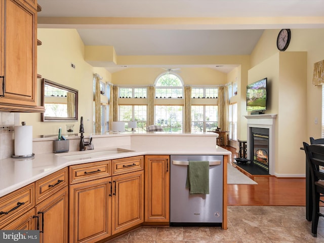 kitchen with dishwasher, vaulted ceiling, sink, and light wood-type flooring