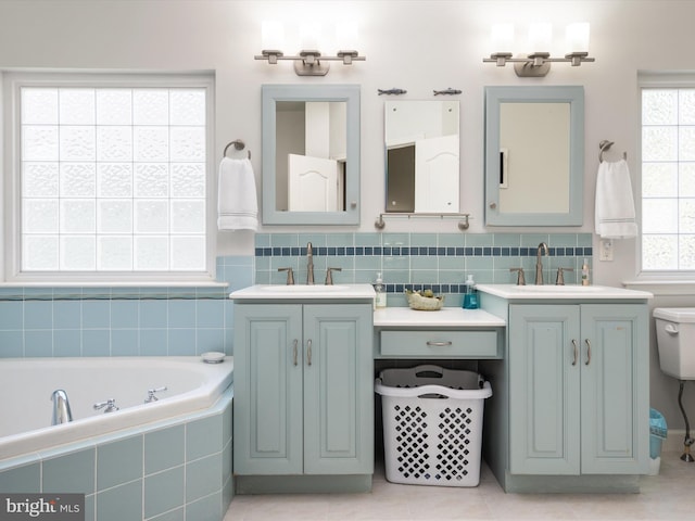 bathroom with tiled tub, vanity, and tile patterned floors