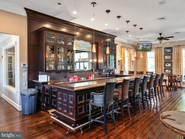 bar featuring ceiling fan, crown molding, dark hardwood / wood-style flooring, decorative light fixtures, and decorative backsplash