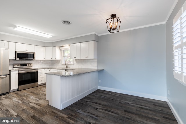 kitchen featuring appliances with stainless steel finishes, backsplash, dark hardwood / wood-style flooring, white cabinets, and ornamental molding