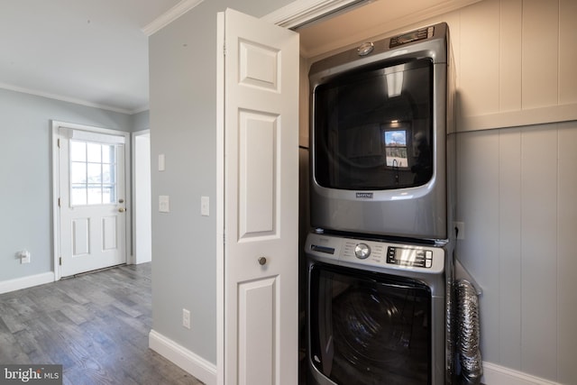 washroom featuring crown molding, stacked washer and clothes dryer, and wood-type flooring