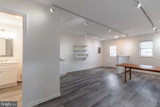 interior space with sink, hardwood / wood-style floors, track lighting, and electric panel