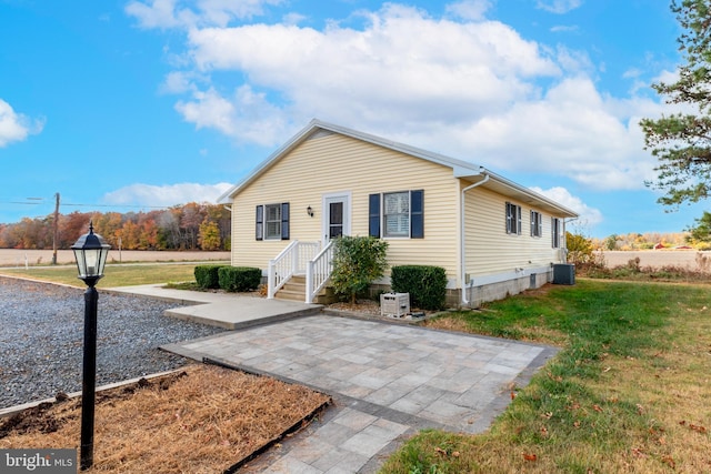 view of front of home featuring central AC, a front yard, and a patio area