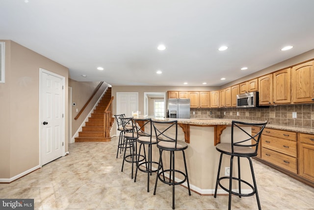 kitchen with decorative backsplash, light stone counters, appliances with stainless steel finishes, a breakfast bar, and a center island