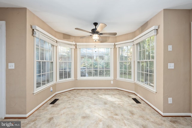 unfurnished sunroom with a healthy amount of sunlight and ceiling fan