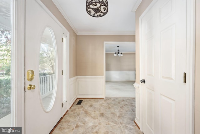 foyer entrance with ornamental molding, a chandelier, and plenty of natural light