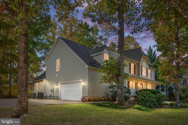 property exterior at dusk with a yard, a garage, and central AC unit