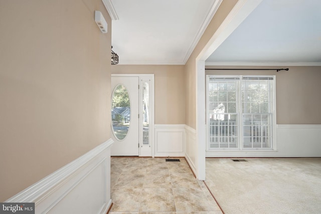 entrance foyer with crown molding and light colored carpet