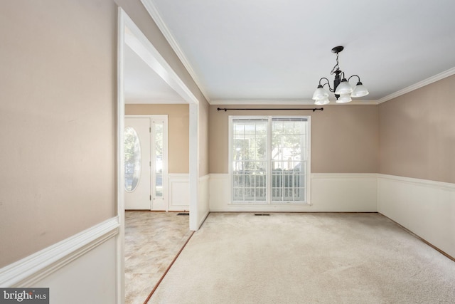 carpeted spare room featuring crown molding and a chandelier