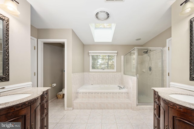 full bathroom featuring toilet, tile patterned flooring, independent shower and bath, vanity, and a skylight