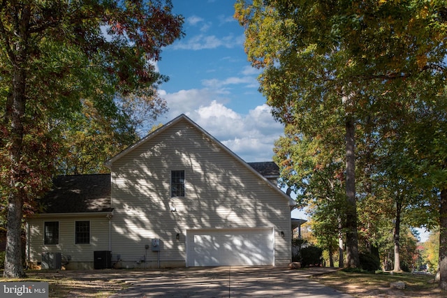 view of side of home with central AC and a garage