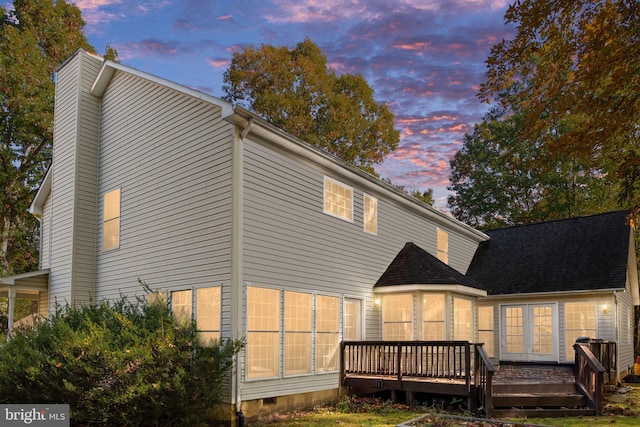 back house at dusk featuring a wooden deck