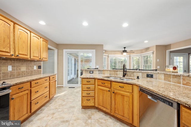 kitchen with stainless steel appliances, sink, light stone countertops, tasteful backsplash, and ceiling fan