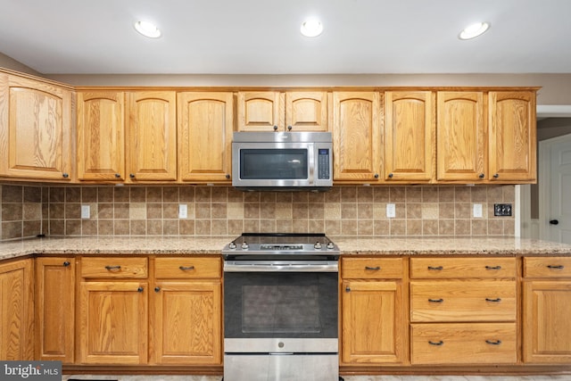 kitchen featuring light stone counters, appliances with stainless steel finishes, and decorative backsplash