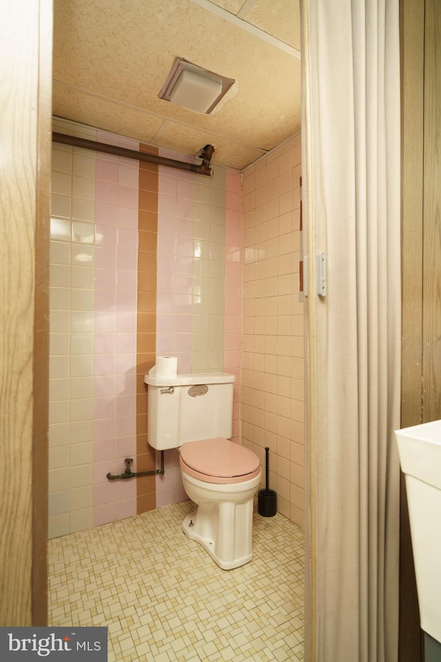 bathroom with sink, toilet, and tile walls