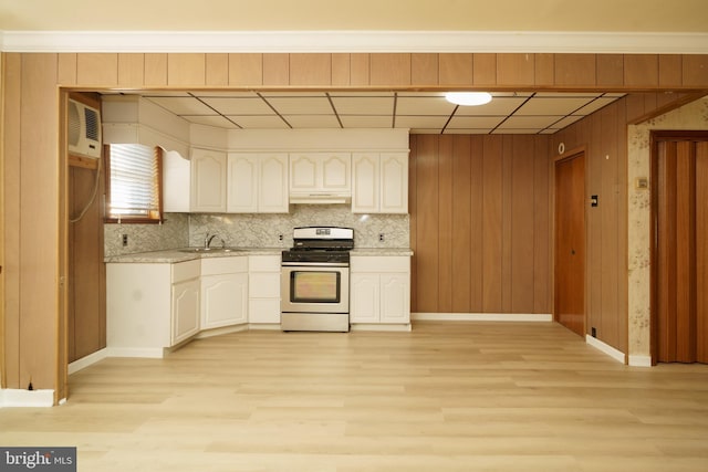 kitchen with stainless steel gas range, a wall mounted AC, sink, light hardwood / wood-style floors, and wood walls