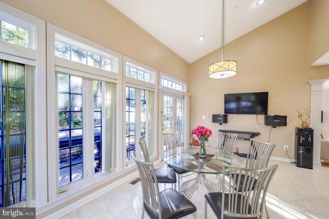 dining room with ornate columns, light tile patterned floors, and lofted ceiling