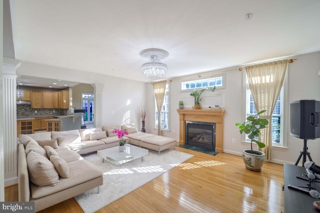 living room with a fireplace, light hardwood / wood-style floors, plenty of natural light, and a notable chandelier