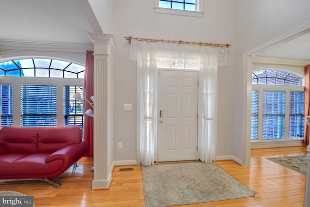 foyer with decorative columns, wood-type flooring, and ornamental molding