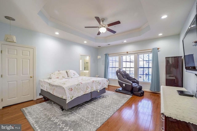 bedroom with hardwood / wood-style flooring, ceiling fan, a raised ceiling, and ornamental molding