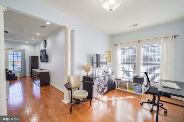 home office with decorative columns, a wealth of natural light, and light hardwood / wood-style flooring