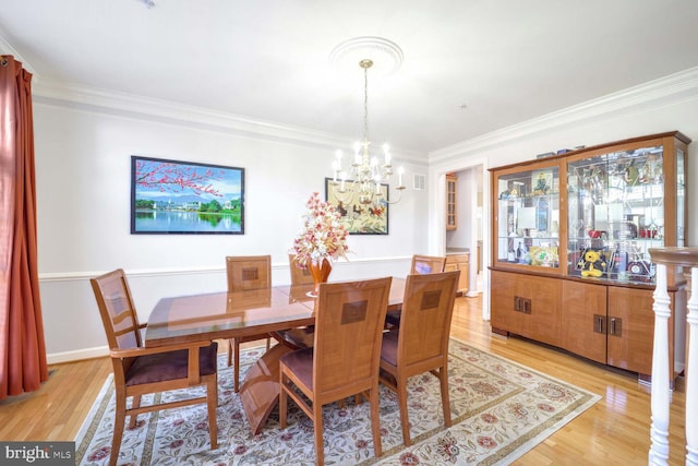 dining room with light wood-type flooring, crown molding, and a chandelier