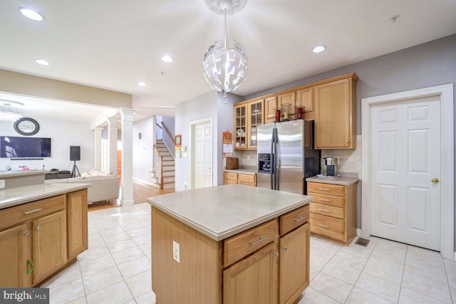 kitchen with stainless steel refrigerator with ice dispenser, light tile patterned floors, decorative light fixtures, and a kitchen island