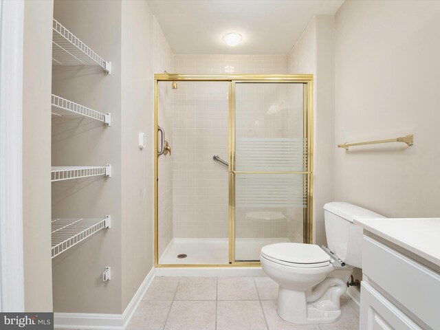 bathroom with toilet, vanity, tile patterned flooring, and a shower with shower door