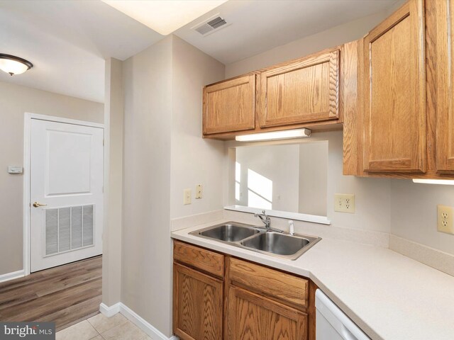 kitchen featuring white dishwasher, sink, and light hardwood / wood-style floors