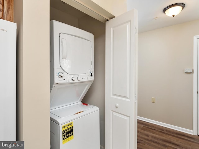 clothes washing area featuring stacked washer / dryer and dark hardwood / wood-style flooring