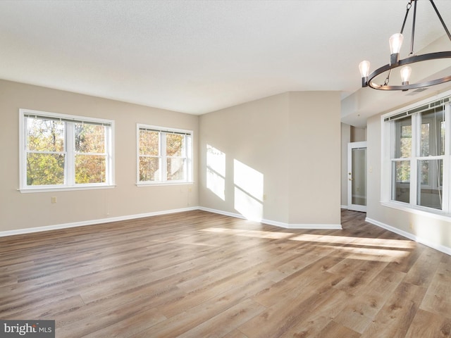 unfurnished living room featuring light wood-type flooring and a notable chandelier