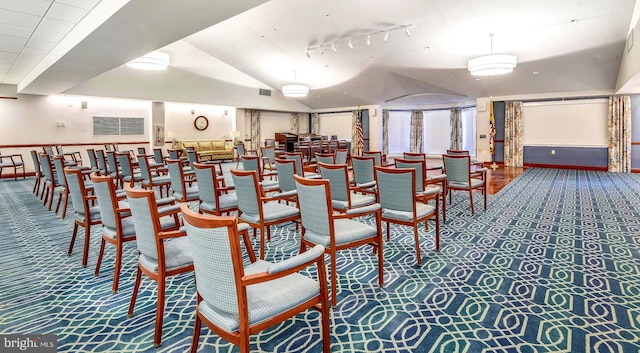 dining room featuring carpet flooring, track lighting, and vaulted ceiling