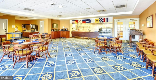 carpeted dining space with a raised ceiling