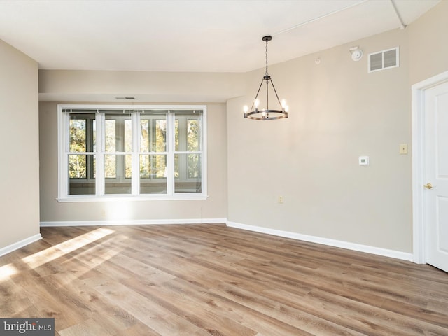 unfurnished dining area featuring hardwood / wood-style flooring and an inviting chandelier