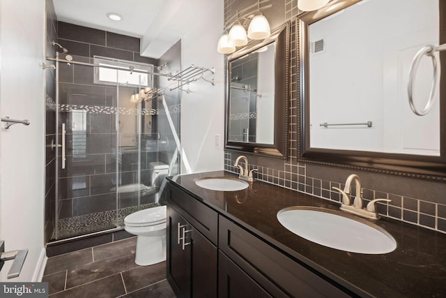 bathroom featuring tile patterned flooring, toilet, backsplash, a shower with shower door, and vanity