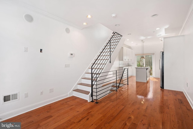 stairway featuring hardwood / wood-style flooring and ornamental molding