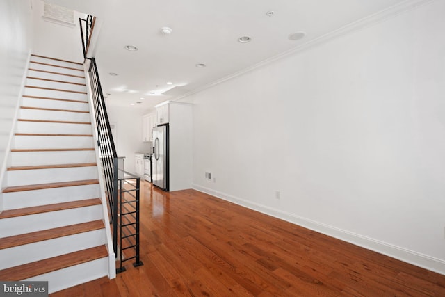 staircase featuring wood-type flooring and ornamental molding