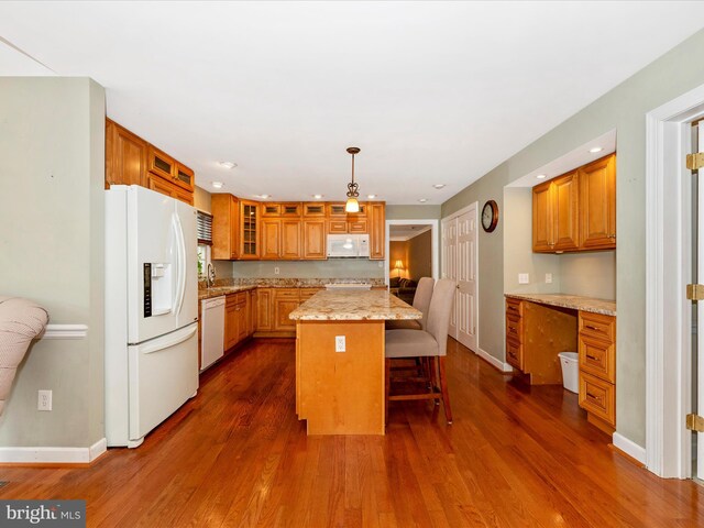 kitchen with hanging light fixtures, dark wood-type flooring, white appliances, and a kitchen island