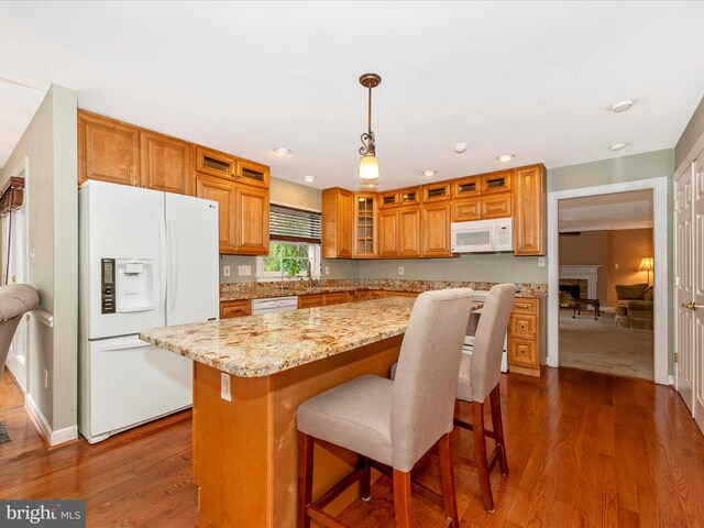 kitchen featuring hanging light fixtures, dark hardwood / wood-style flooring, white appliances, and a center island