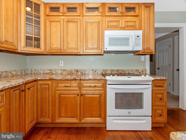 kitchen with light stone counters, dark wood-type flooring, and white appliances