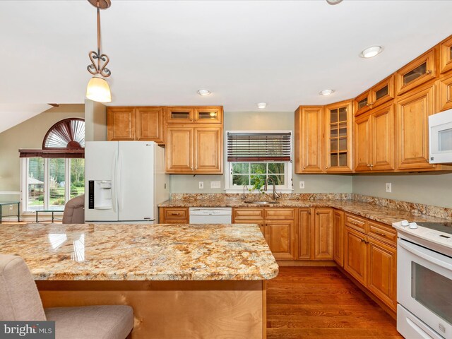 kitchen with pendant lighting, white appliances, sink, light stone countertops, and dark hardwood / wood-style floors