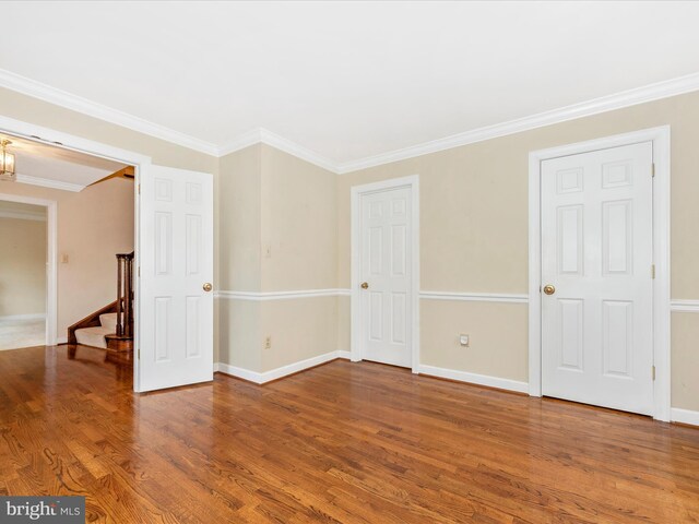 spare room featuring wood-type flooring and crown molding