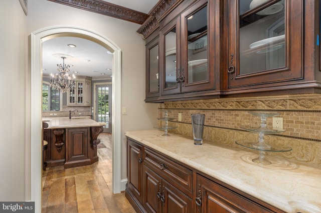 bar with dark brown cabinetry, decorative backsplash, and light hardwood / wood-style floors